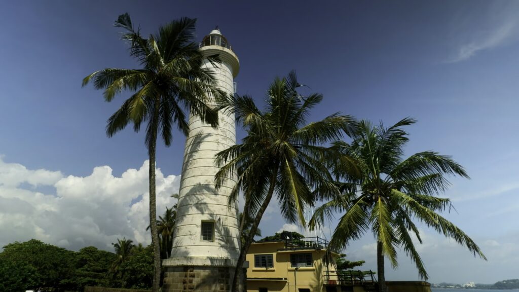 Galle Lighthouse at Galle Fort, Sri Lanka. Action. Beautiful palm trees and blue cloudy sky.