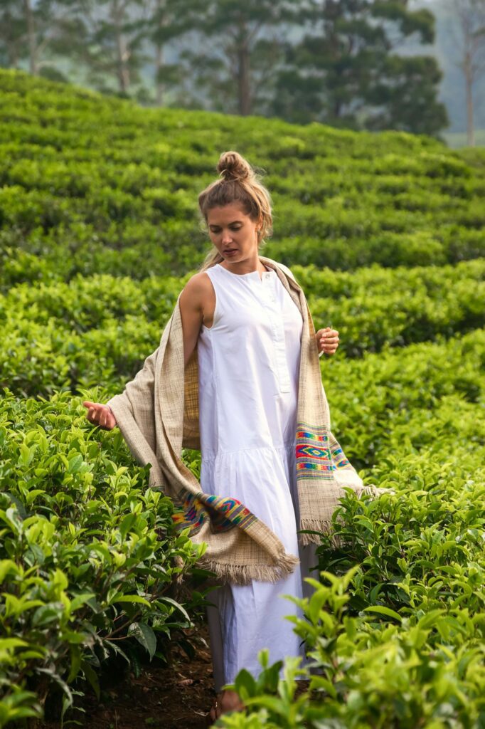 Young woman in casual traditional white clothes at tea plantation background landscape in Sri Lanka
